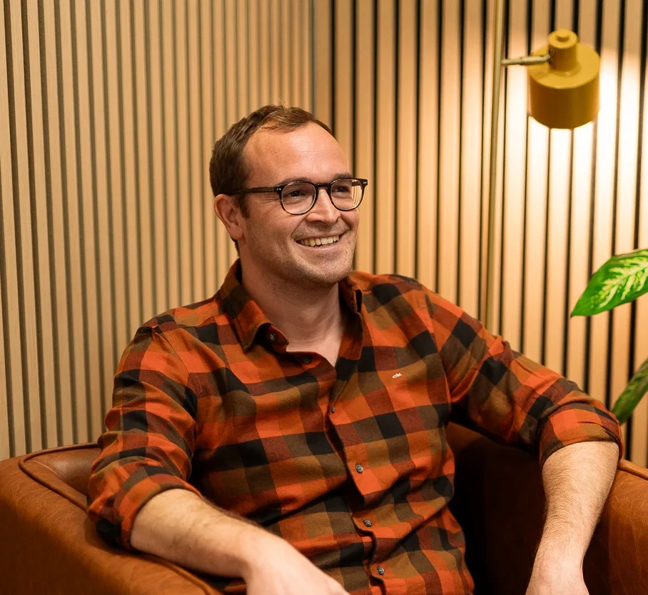 DJ Alois in privaten Klamotten auf einem braunen Stuhl