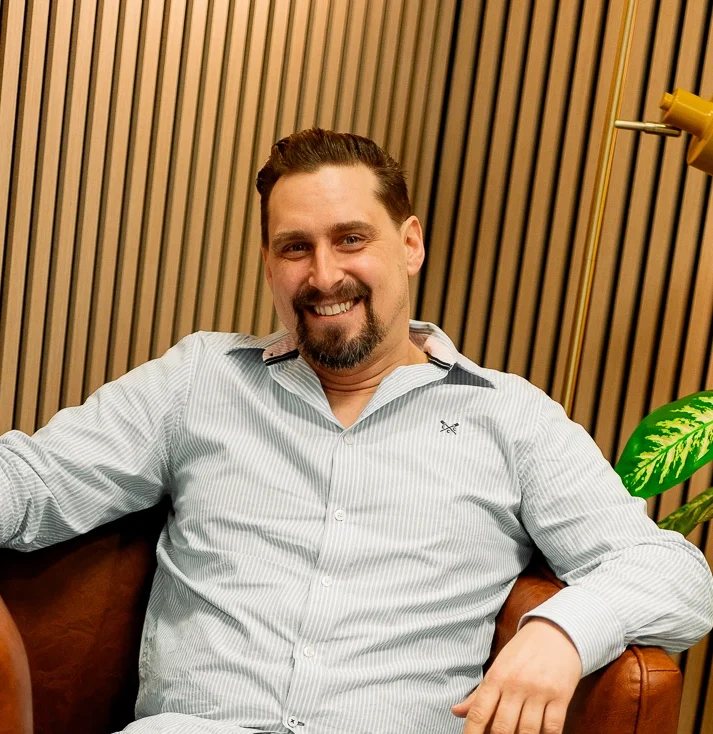 DJ Stefan vor Holzhintergrund lacht in die Kamera