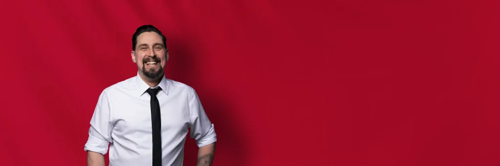 DJ Stefan vor rotem Hintergrund lächelnd