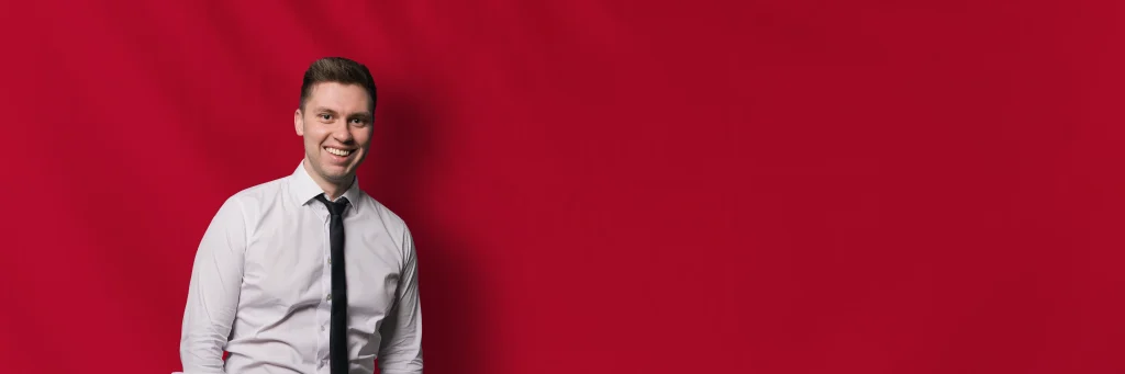 DJ Sam vor rotem Hintergrund lächelnd